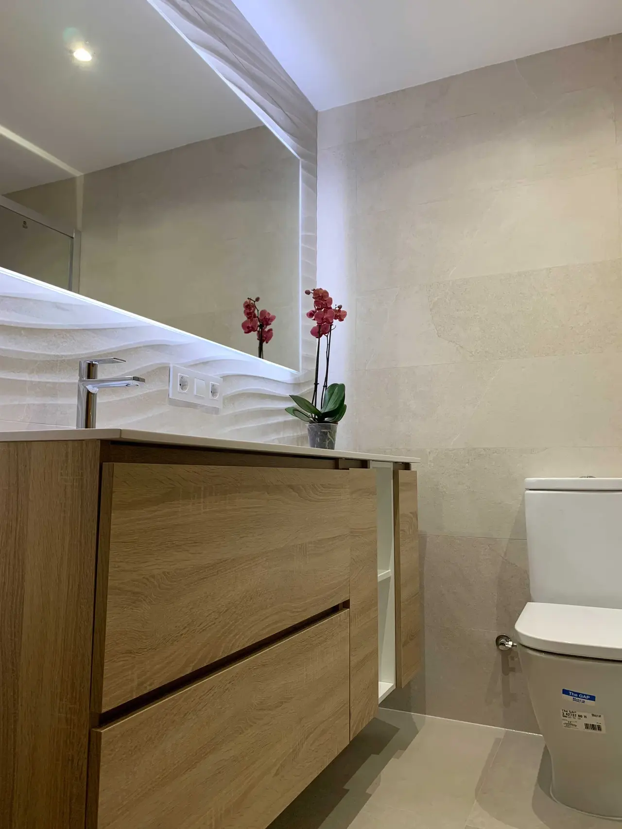 Mueble de baño con encimera ondulada y orquídea