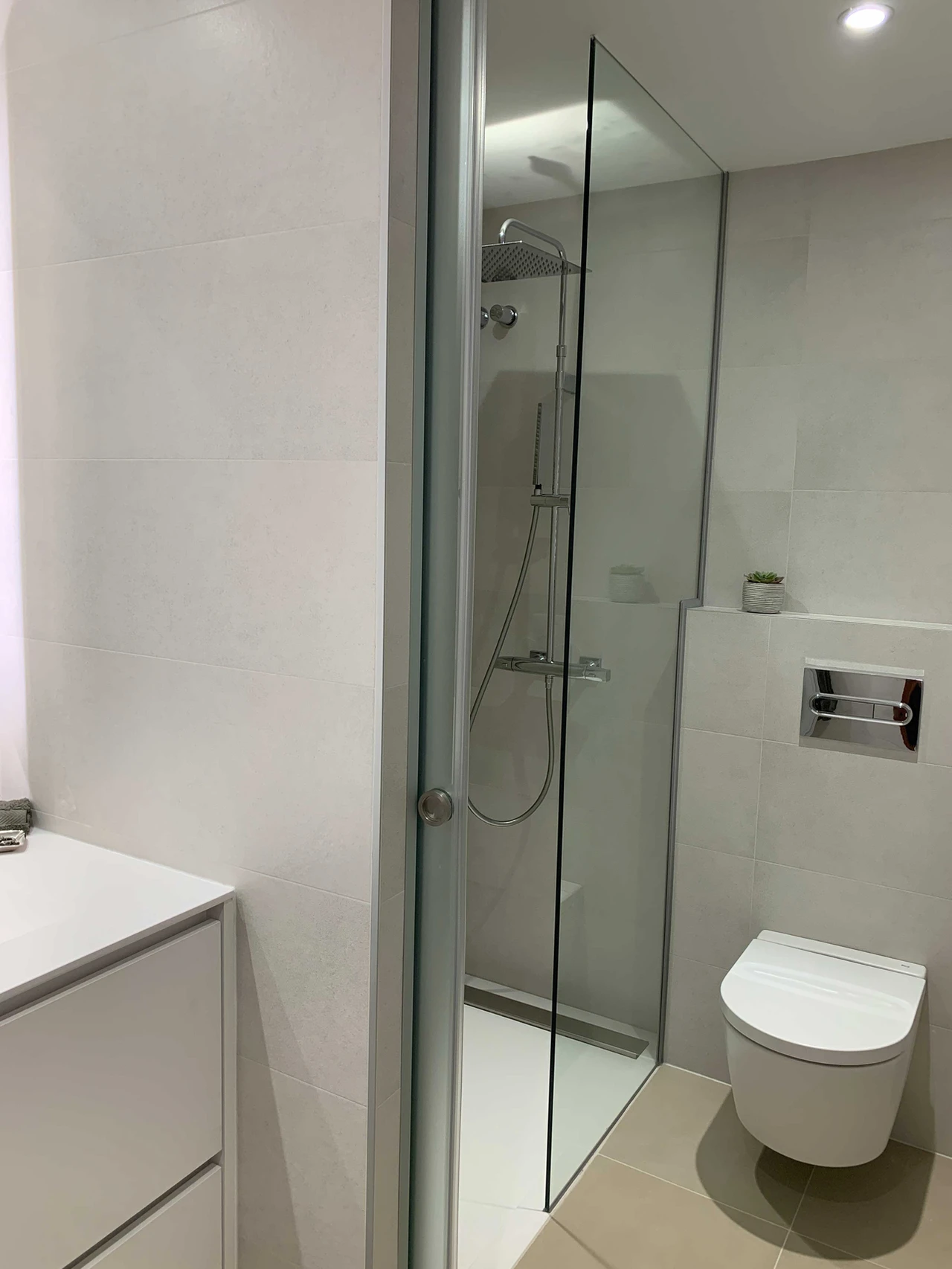 Baño con ducha a ras de suelo y mampara transparente